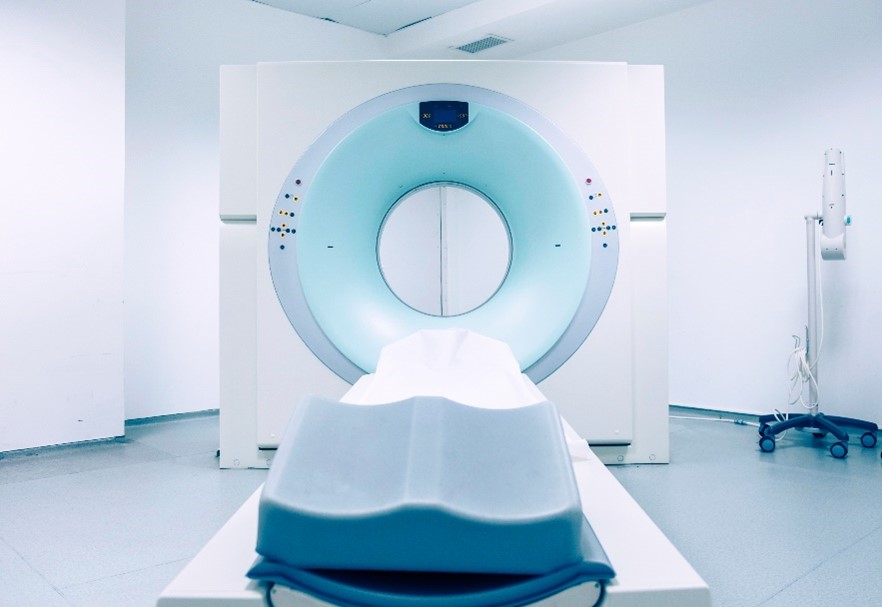 An image of an MRI machine in a white hospital room.