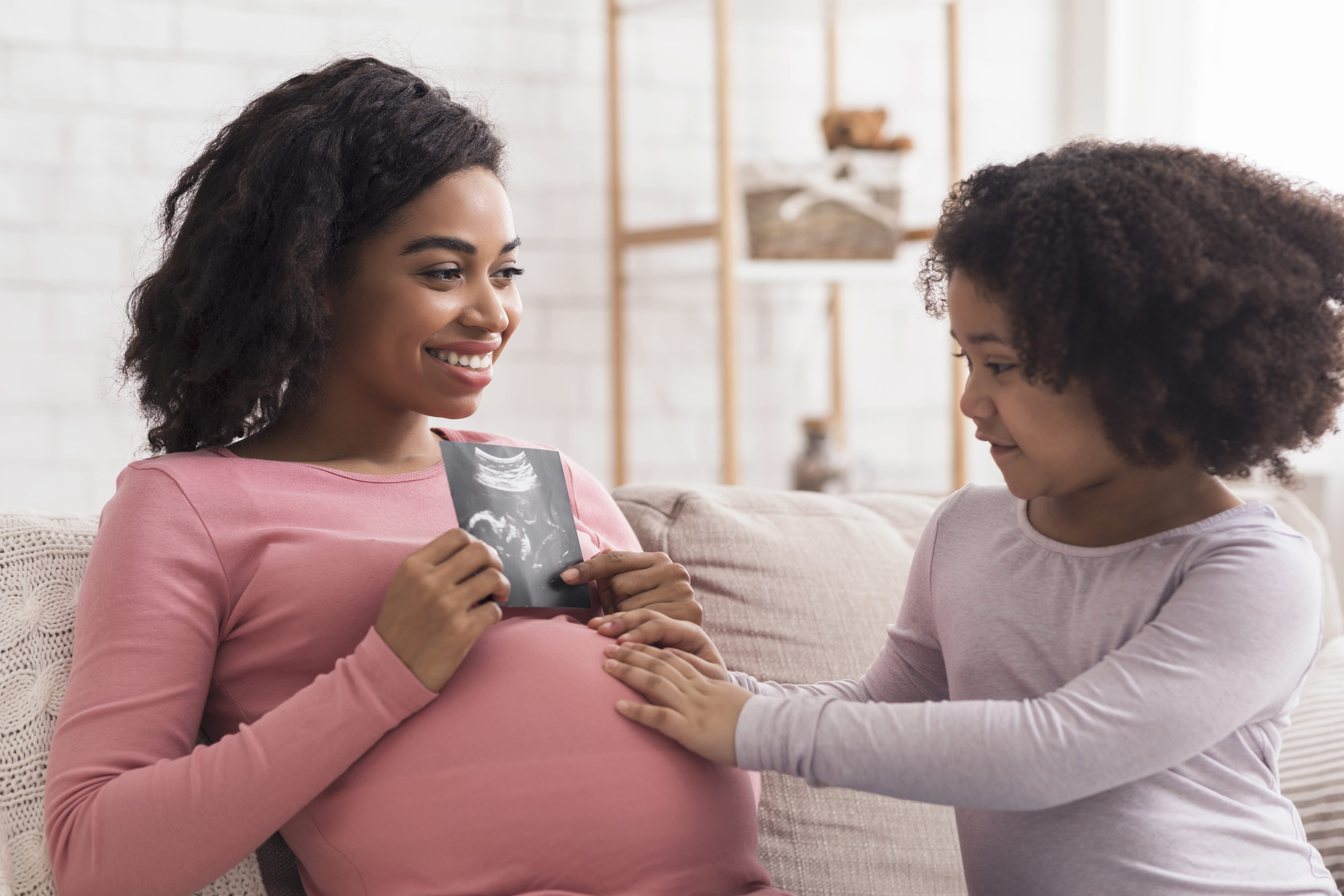 Excited Pregnant Black Woman Showing Baby Ultrasound Scan To Her Daughter